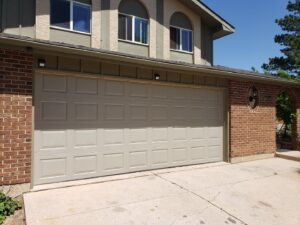 An exterior view of a beige garage door on a residential home, serviced by Black Forest Door Repair in Colorado Springs, CO.