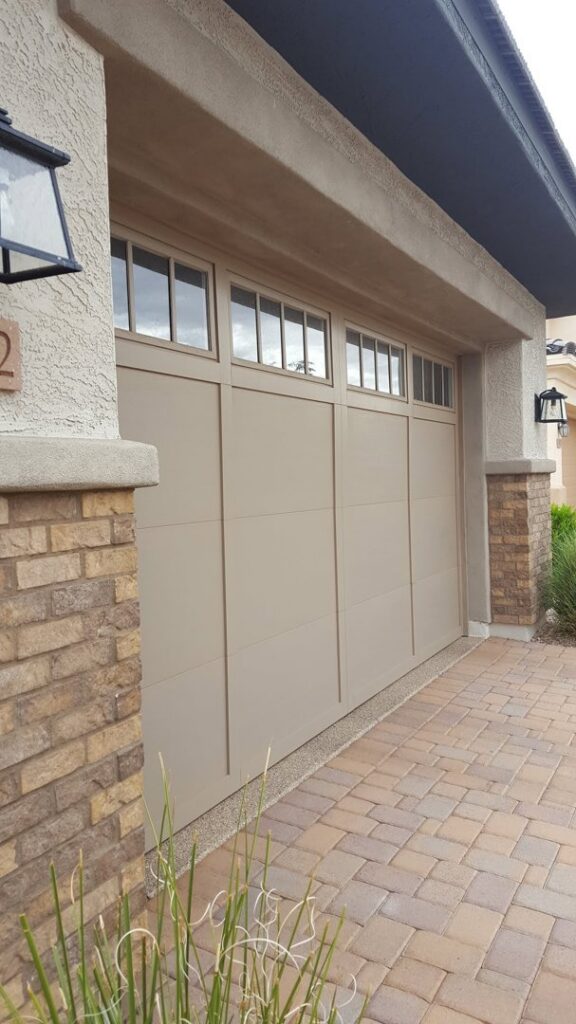 A stylish beige garage door with windows installed on a home by Absolute Garage Doors LLC AZ in Mesa, AZ