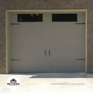 A beige garage door with decorative windows and hardware installed by Access Garage Doors-Chattanooga, TN