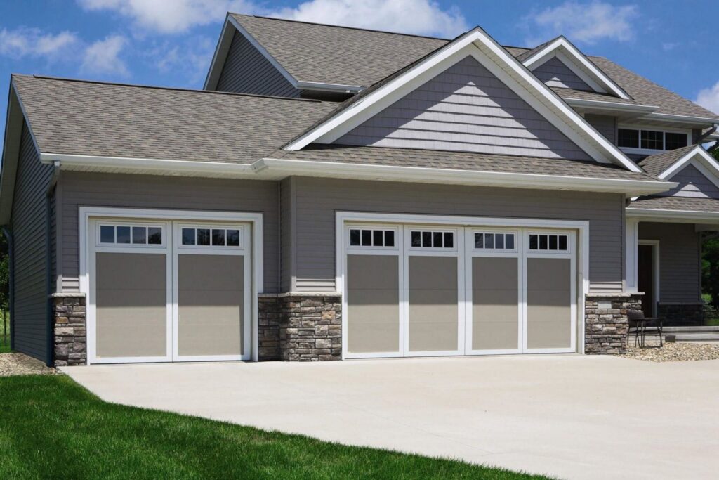 Beige garage doors with windows and stone accents installed by Overhead Door Company of Salem in Salem, OR.