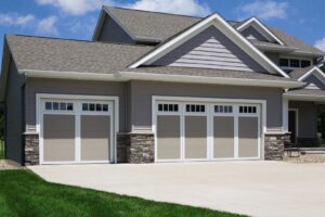 Beige garage doors with windows and stone accents installed by Overhead Door Company of Salem in Salem, OR.