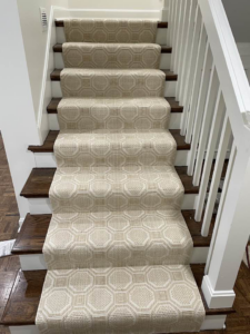 A newly installed beige patterned carpet runner on a wooden staircase by Jimmy's Flooring in Louisville, KY