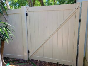A close-up view of a newly installed beige vinyl fence gate by Gaines Fence in Jacksonville, FL.