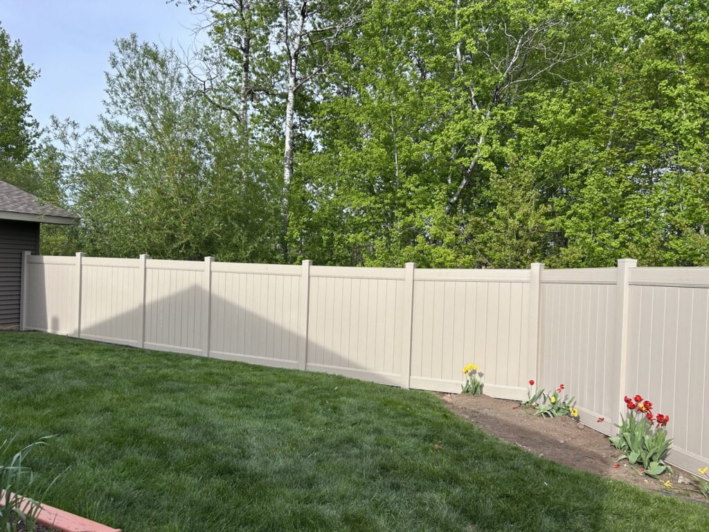 A clean beige vinyl privacy fence installed in a residential backyard by North Shore Fence Company in Centereach, NY.