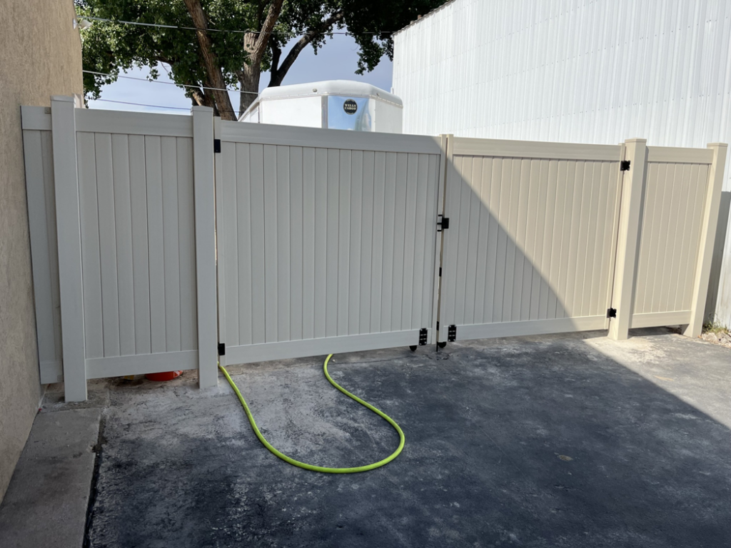 A newly installed beige vinyl privacy fence with a double gate by Border Fence, Inc. in Greeley, CO.