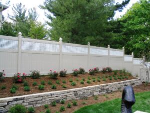 A beige vinyl privacy fence with a decorative lattice top, installed by Custom Design Fence & Deck, Inc. in Ofallon, MO