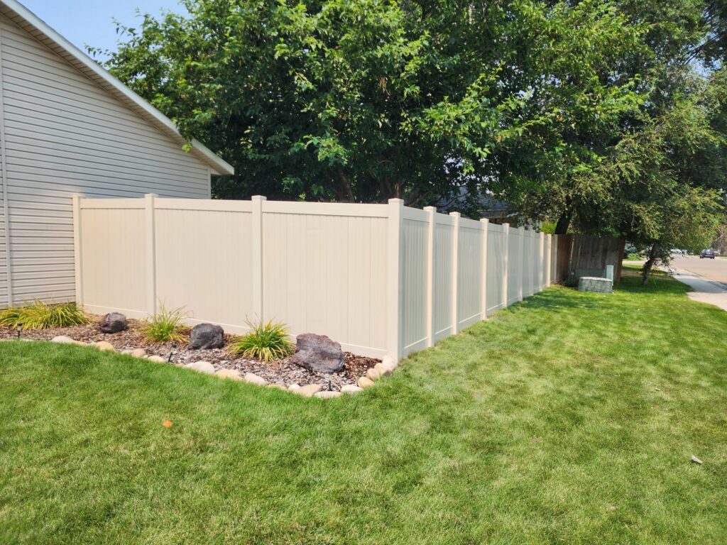 A newly installed beige vinyl privacy fence in a residential backyard by Josey's Fencing LLC in Caldwell, ID.
