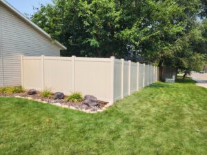 A newly installed beige vinyl privacy fence in a residential backyard by Josey's Fencing LLC in Caldwell, ID.
