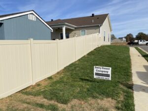 A newly installed beige vinyl privacy fence with a Petty Fence Company LLC sign in Evansville, IN.
