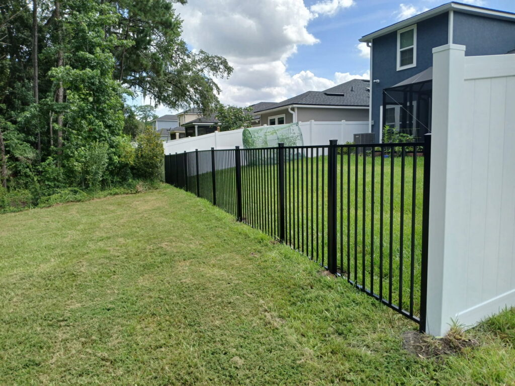 A combination of black aluminum and white vinyl fencing installed in a backyard by Top Fence LLC in Jacksonville, FL.