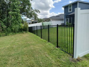 A combination of black aluminum and white vinyl fencing installed in a backyard by Top Fence LLC in Jacksonville, FL.