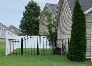 A black aluminum fence with an arched gate complementing a white vinyl privacy fence by Pro Fence in Decatur, AL