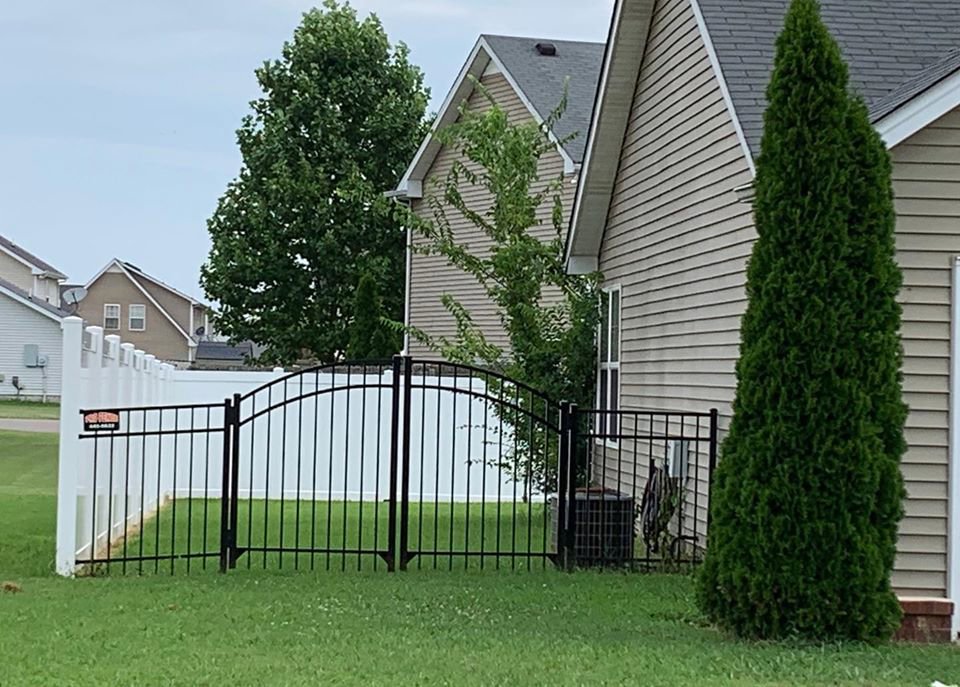 A black aluminum fence with an arched gate complementing a white vinyl privacy fence by Pro Fence in Decatur, AL