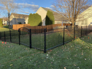 A newly installed black ornamental aluminum fence with an arched gate in a backyard by Safe Yard Fence - Waukesha County in Waukesha, WI.