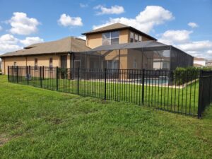 A black aluminum fence installed around a backyard with a pool cage by Big Jerry's Fencing of Boise ID in Holly Springs, NC.