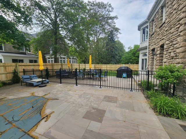 A black aluminum fence installed around a residential patio and pool area by City Fence Inc. in Lancaster, NY.