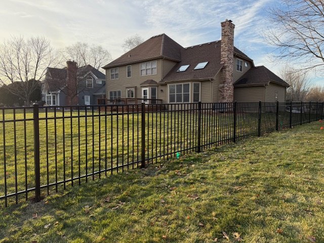 A black aluminum fence installed in a residential backyard by Cedar Mountain Fence Company in Plainfield, IL.