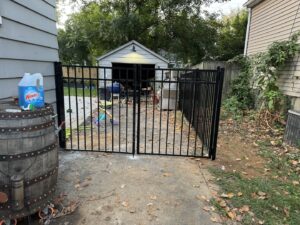 A black aluminum fence with a double gate installed in a backyard by Shatkoff Fencing in Louisville, KY.