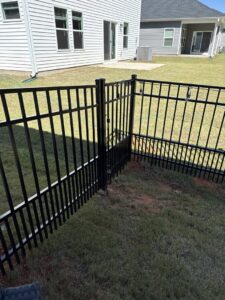 A black aluminum fence with a gate creating a small enclosure by Superior Fence & Rail of Charlotte, NC