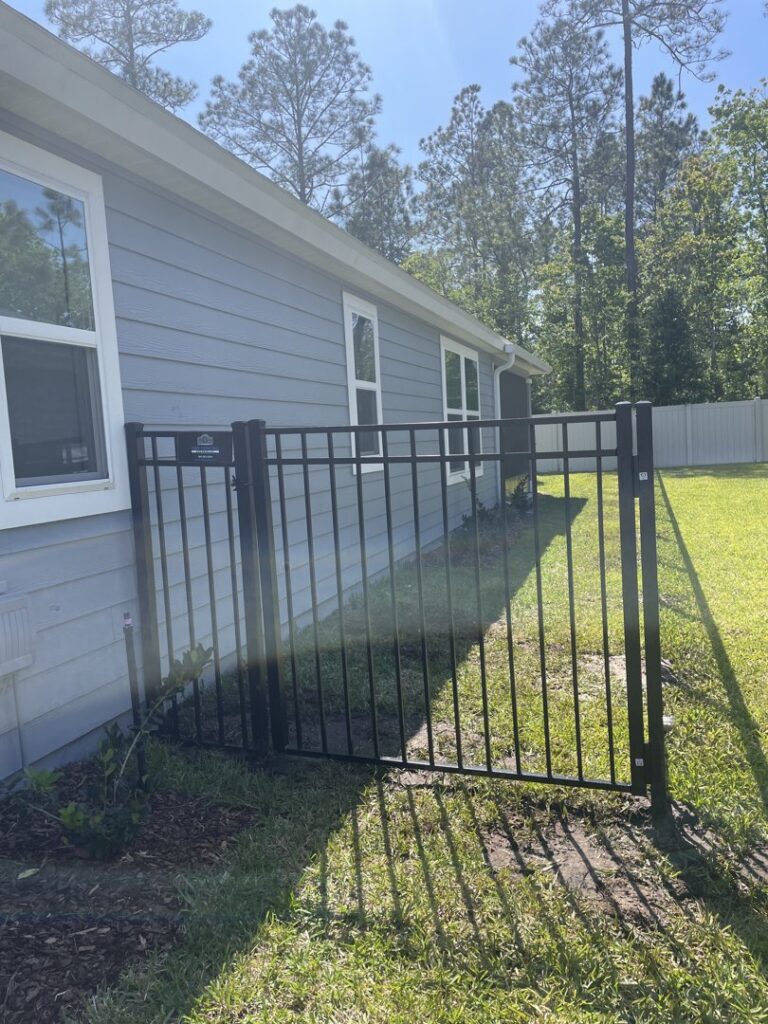 A black aluminum fence and gate installed next to a residential home by R&R Fence Services in Jacksonville, FL.