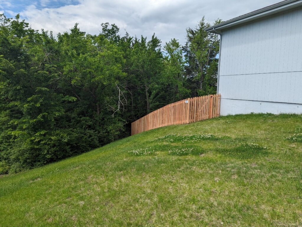 A black aluminum fence with a gate featuring the Royal Fence & Design LLC sign in Olathe, KS.