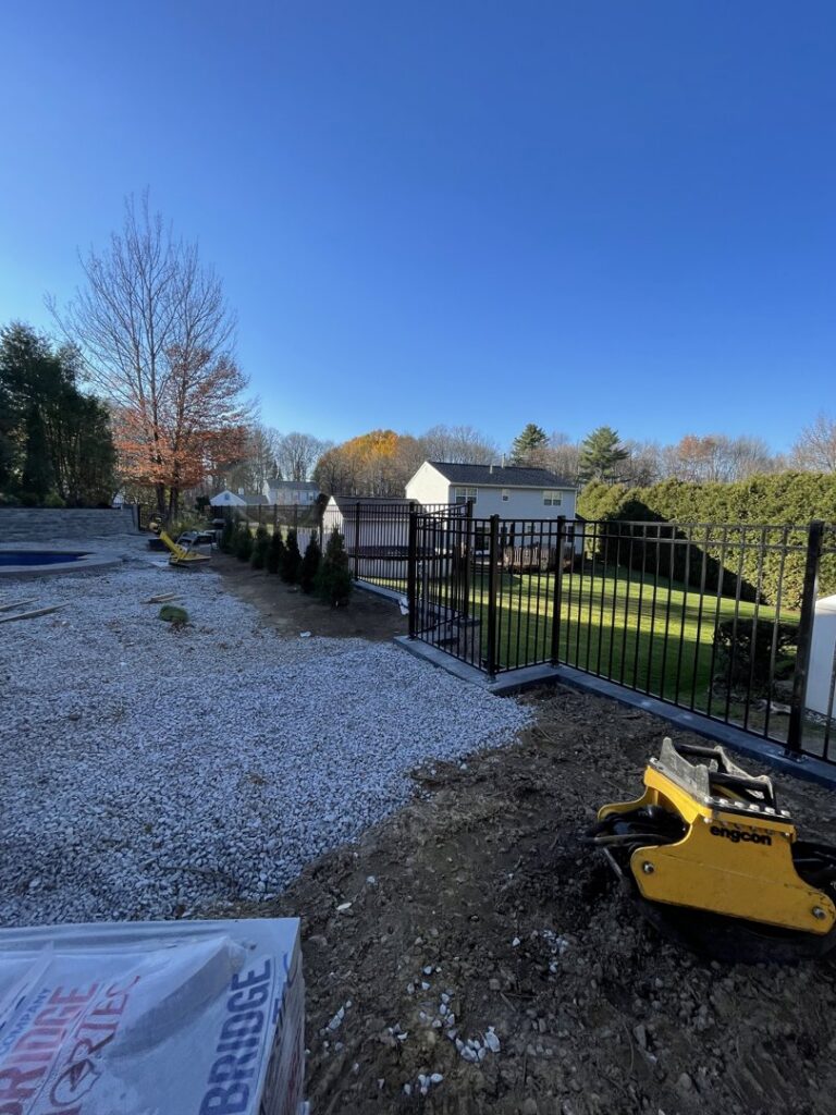 A black aluminum fence installed alongside a gravel path, part of a landscaping project by Vision One Construction LLC in Schenectady, NY