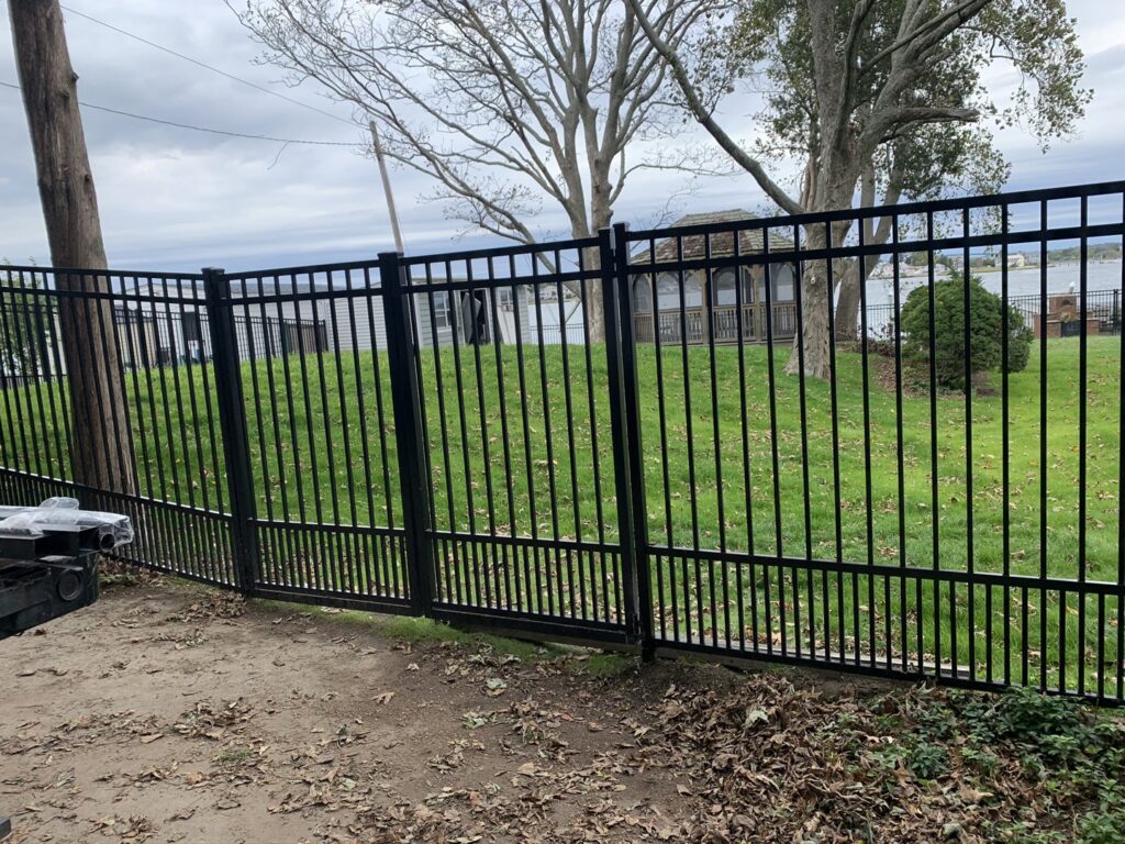 Black aluminum fence with a gate installed by Louis Fence installations & repairs in Fall River, MA