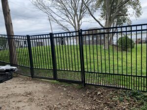 Black aluminum fence with a gate installed by Louis Fence installations & repairs in Fall River, MA
