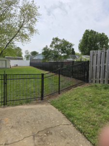 A newly installed black aluminum fence with a gate in a residential backyard by Outsiders Fencing in Greensboro, NC.