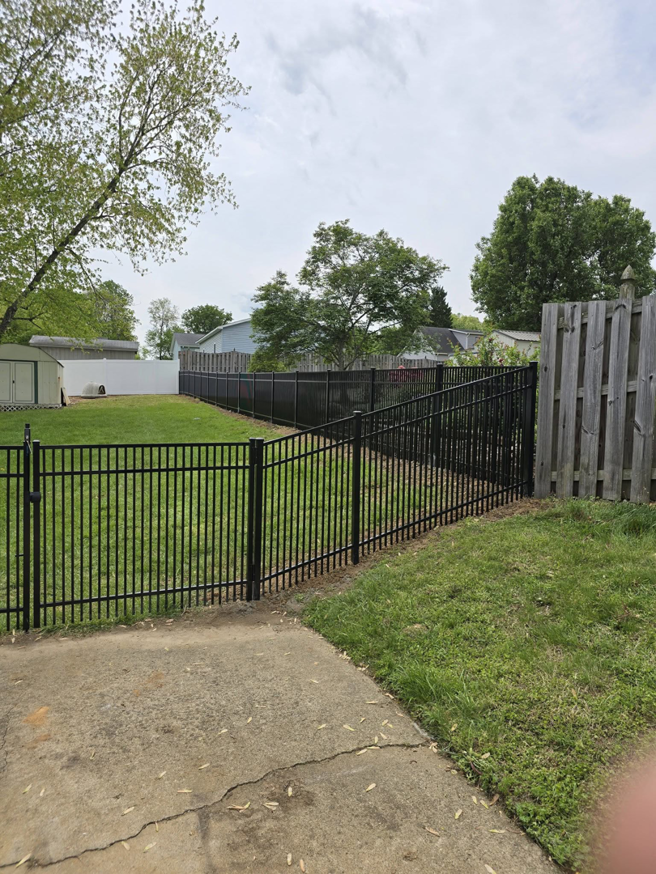 A newly installed black aluminum fence with a gate in a residential backyard by Outsiders Fencing in Greensboro, NC.