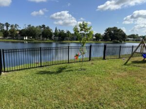 A black aluminum fence providing security and clear views for a lakefront property by Fence Nation LLC in Jacksonville, FL.
