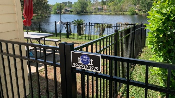 A black aluminum fence installed along a lakefront property by Top Fence LLC in Jacksonville, FL.