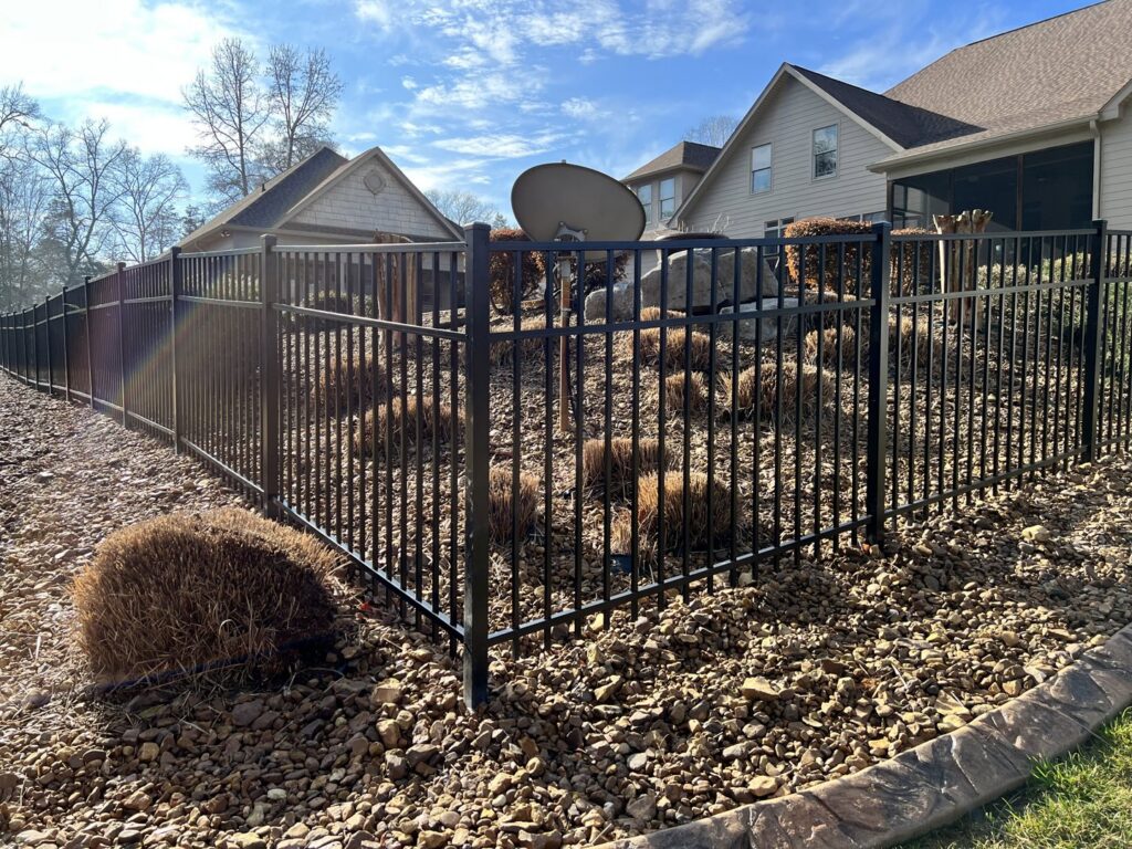A black aluminum fence enclosing a beautifully landscaped yard with rocks and shrubs, installed by Holmes Fence Company in Chattanooga, TN.