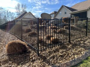 A black aluminum fence enclosing a beautifully landscaped yard with rocks and shrubs, installed by Holmes Fence Company in Chattanooga, TN.