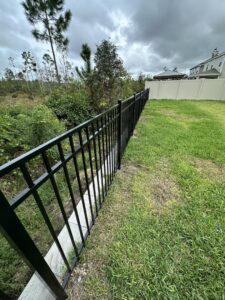 A black aluminum fence bordering a natural landscape, installed by Masters Fence Contracting in Jacksonville, FL.