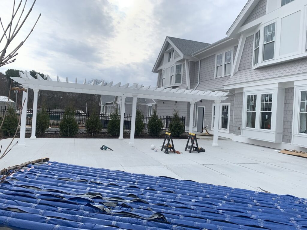 Black aluminum fence installed behind a white pergola by Louis Fence installations & repairs in Fall River, MA