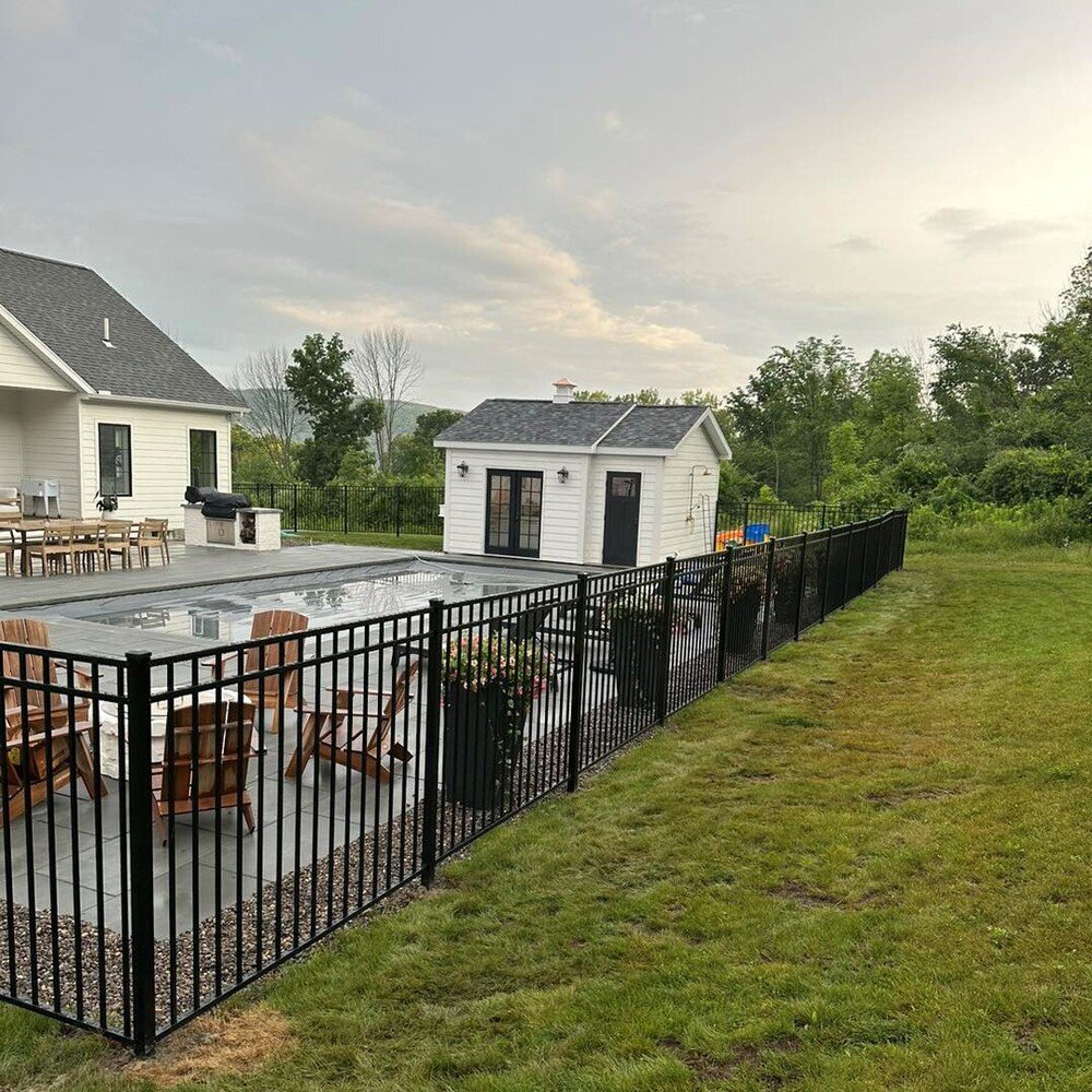 A black aluminum fence enclosing a modern pool and patio area, installed by Vision One Construction LLC in Schenectady, NY
