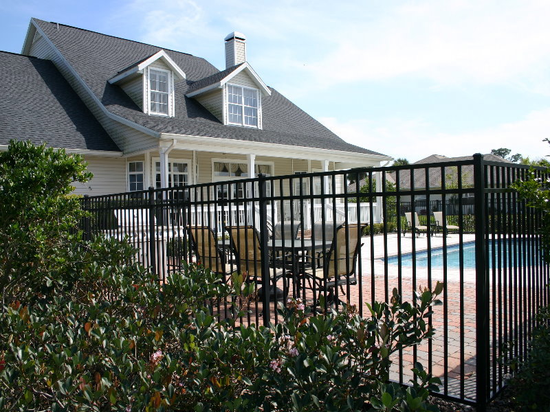 A black aluminum fence surrounding a poolside patio area by Frontier Fence LLC Bowling Green,Ky