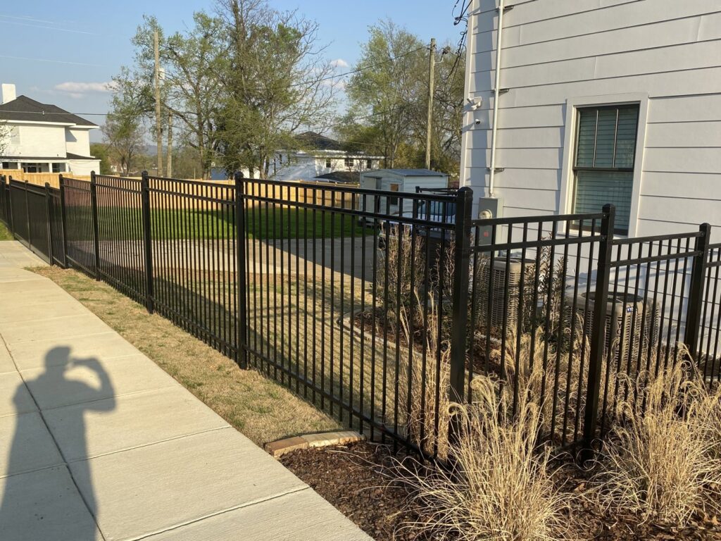 A newly installed black aluminum fence along the side of a residential property by Premier Fence of Birmingham, LLC in Warrior, AL.