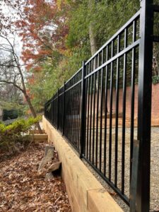 A black aluminum fence installed on top of a wooden retaining wall by Master Fences in Gaithersburg, MD.