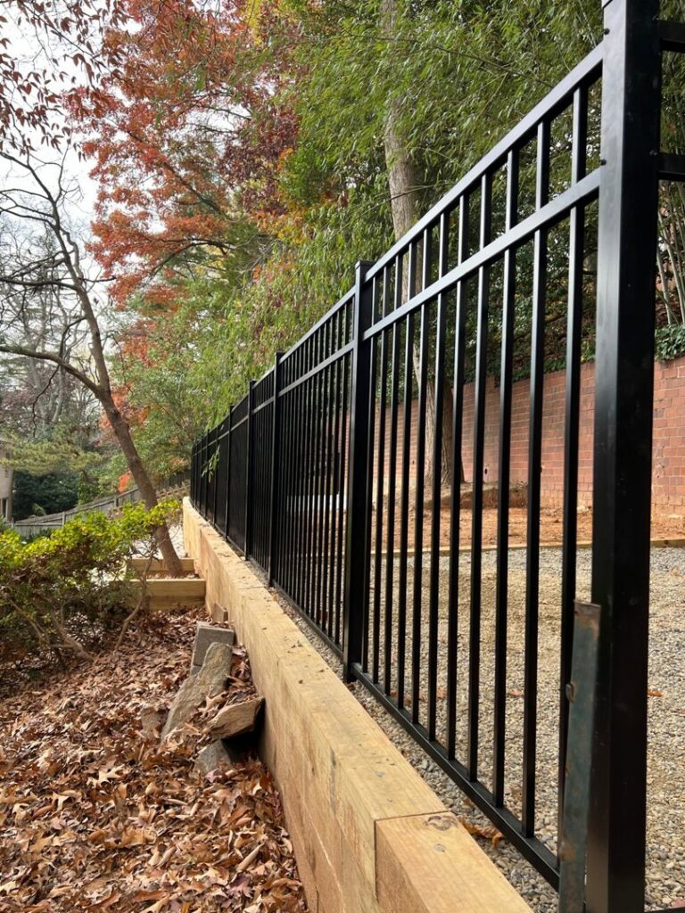 A black aluminum fence installed on top of a wooden retaining wall by Master Fences in Gaithersburg, MD.