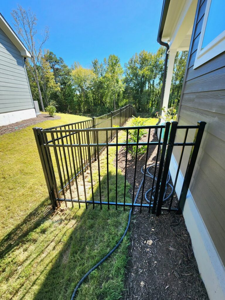 A black aluminum fence with a gate installed in a residential side yard by Endurance Fence Solutions, LLC in Holly Springs, NC