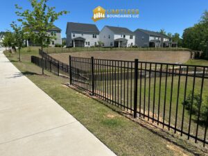 A sleek black aluminum fence installed along a sidewalk and retaining wall by Limitless Boundaries LLC in Garner, NC.