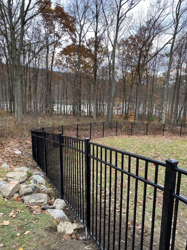 A black aluminum fence installed on a sloped terrain overlooking water by The Fence Dr. in Scranton, PA.