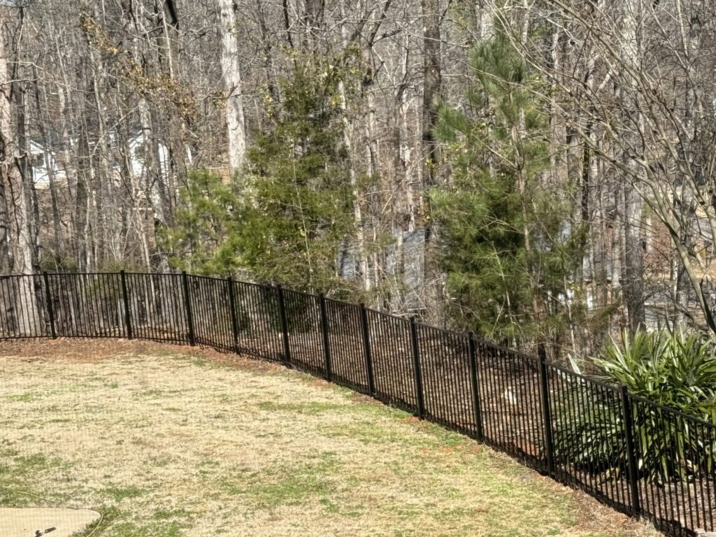 A durable black aluminum fence installed on a sloped residential yard by OneGuard Fencing in Vestavia Hills, AL.