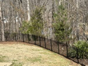 A durable black aluminum fence installed on a sloped residential yard by OneGuard Fencing in Vestavia Hills, AL.
