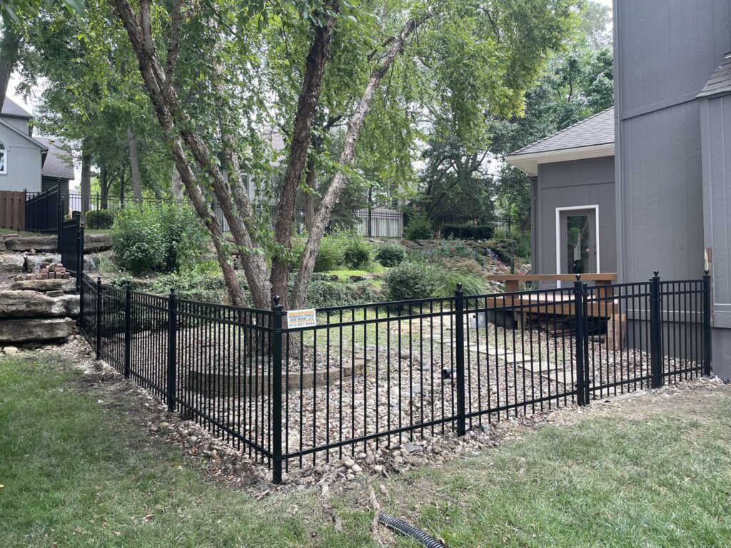 A black aluminum fence installed around a sloped backyard by Sergio's Fence in Kansas City, KS.