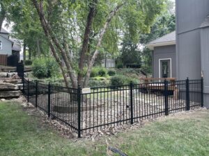 A black aluminum fence installed around a sloped backyard by Sergio's Fence in Kansas City, KS.
