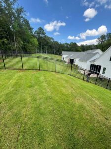 A black aluminum fence installed on a sloped residential property by Smithfield Fence in Crowder, MS.