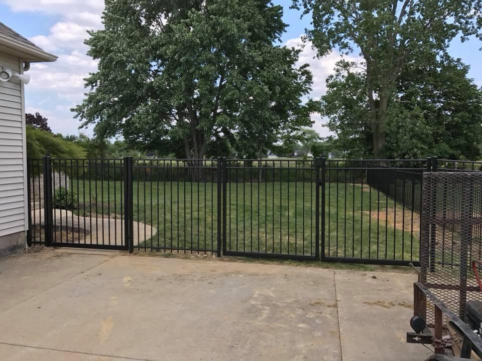 A black aluminum fence with a gate enclosing a backyard area by Budget Fence of Ohio in Cleveland, OH.